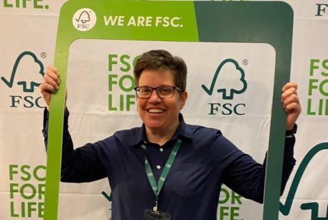 Person smiles while holding a “We Are FSC” frame in front of an FSC-branded backdrop.