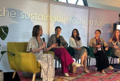 Five speakers sit on stage discussing sustainability at the Sustainable Fashion Forum.