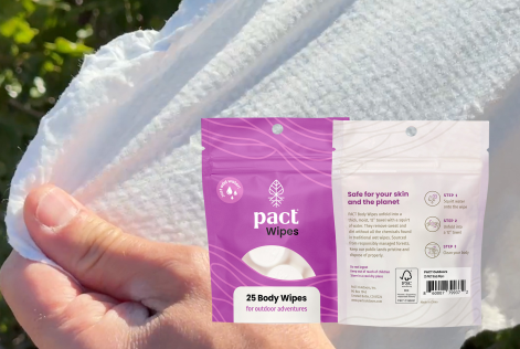Image of PACT body wipes packaging over person's hand stretching a wipe