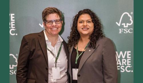 Two attendees smiling in front of the “We Are FSC” background.