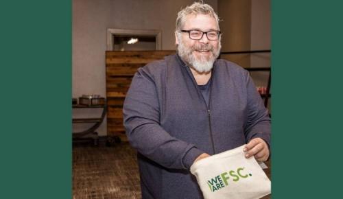 Attendee smiling while holding a “We Are FSC” bag.