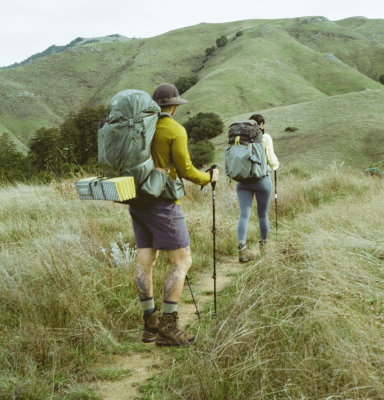 Two overnight backpackers hiking along a pristine mountain trail. 