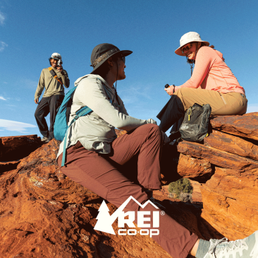 Three backpackers resting at a scenic vista in the desert. 
